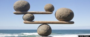 Rocks balancing on driftwood, sea in background